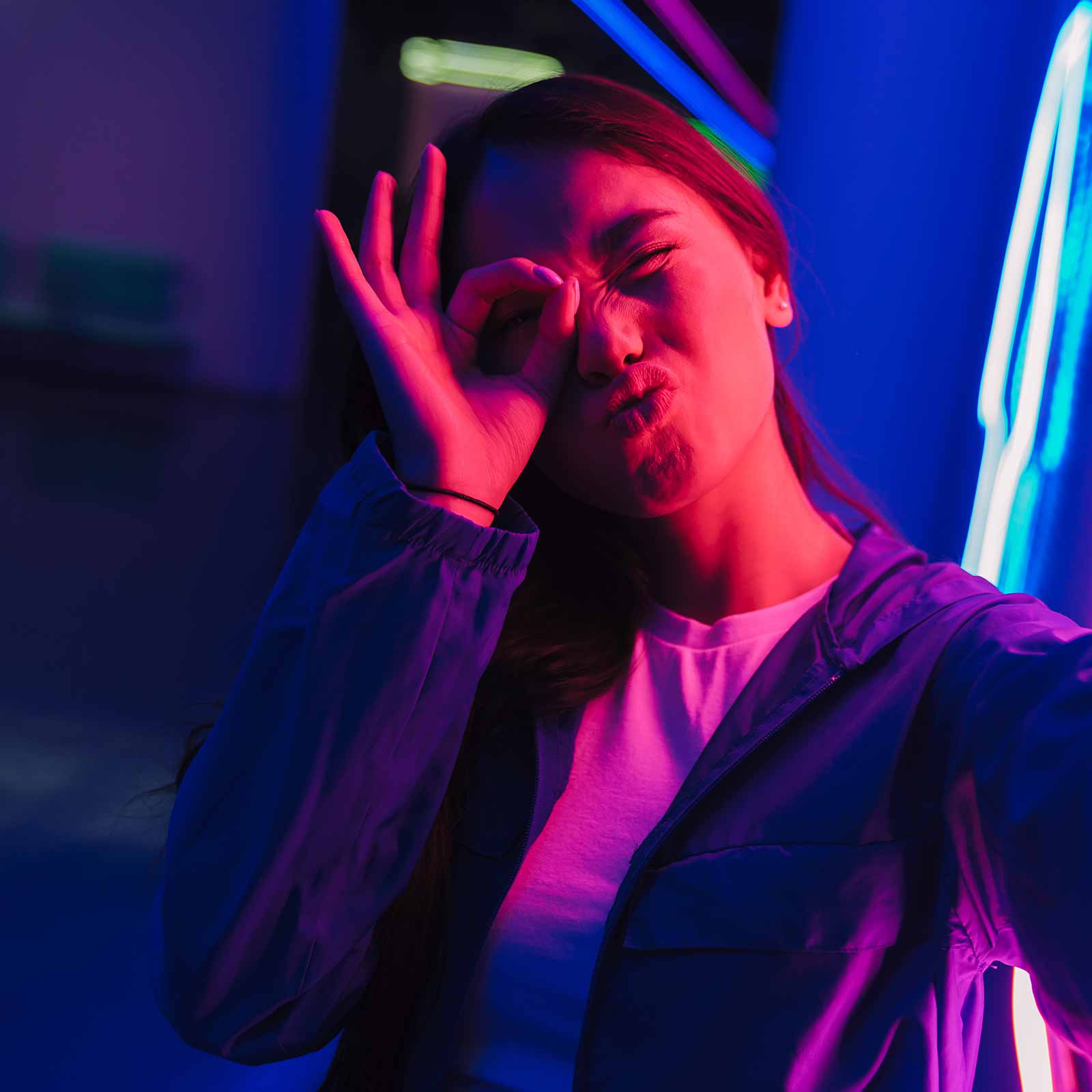 Teen girl posing for a selfie in front of neon lights