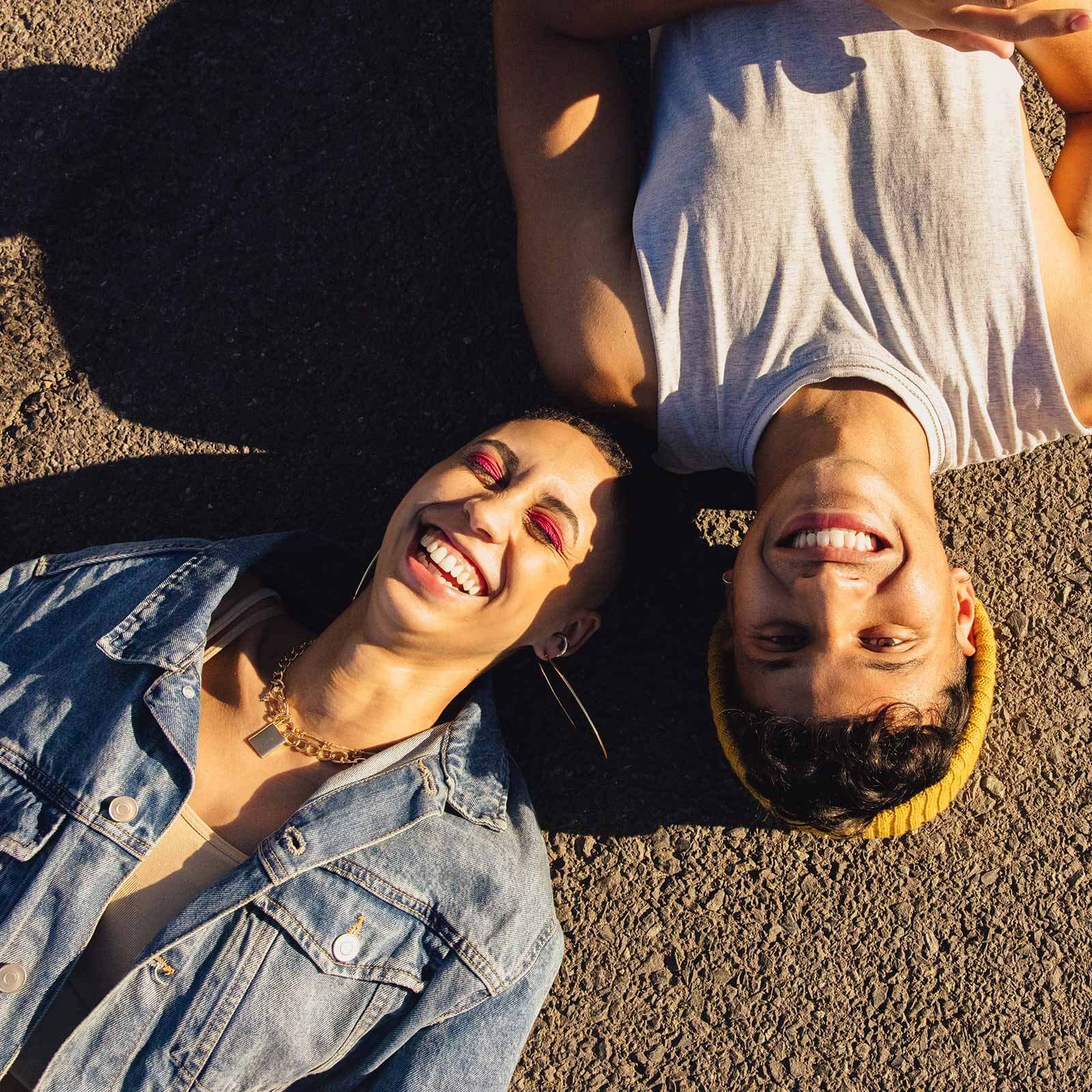 Close up of faces of two young people laying on the ground smiling