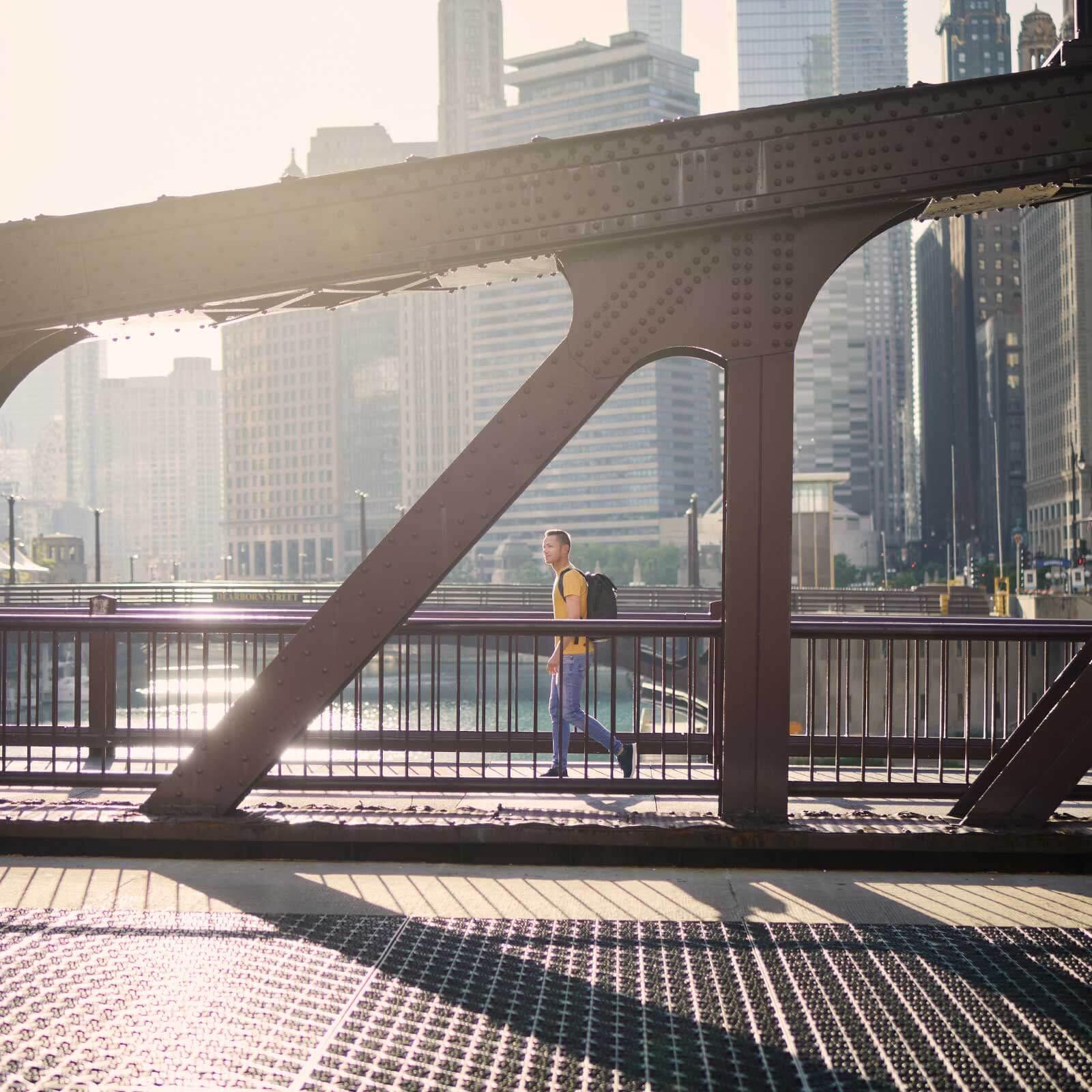 View of a city through a bridge with a pedestrian walking in the distance