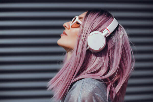 Woman with lilac hear leaning back and wearing headphones