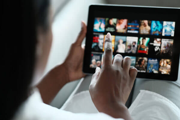 Close up of womans hand using a tablet to browse streaming programmes