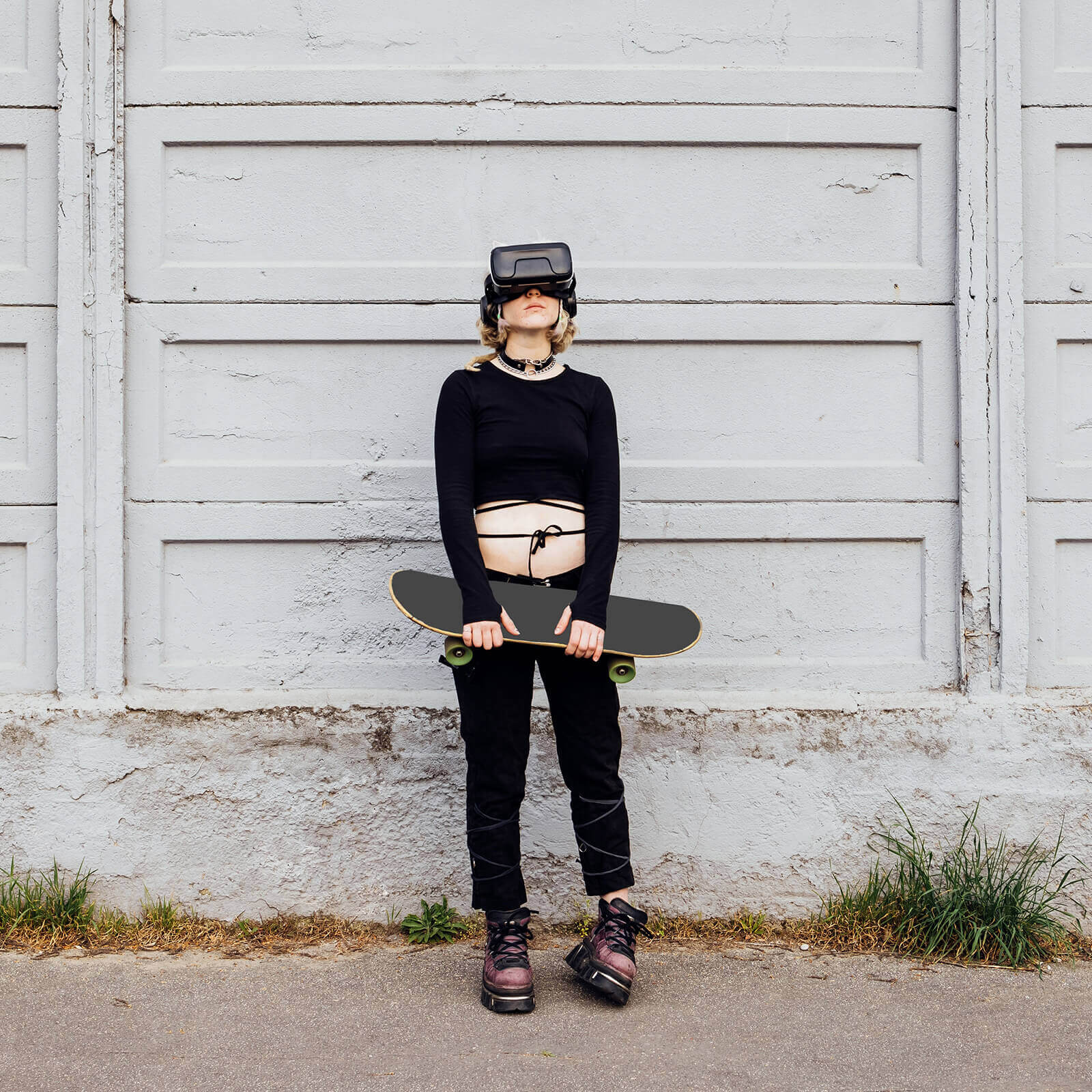 Teenage girl wearing a VR headset and holding a skateboard outside